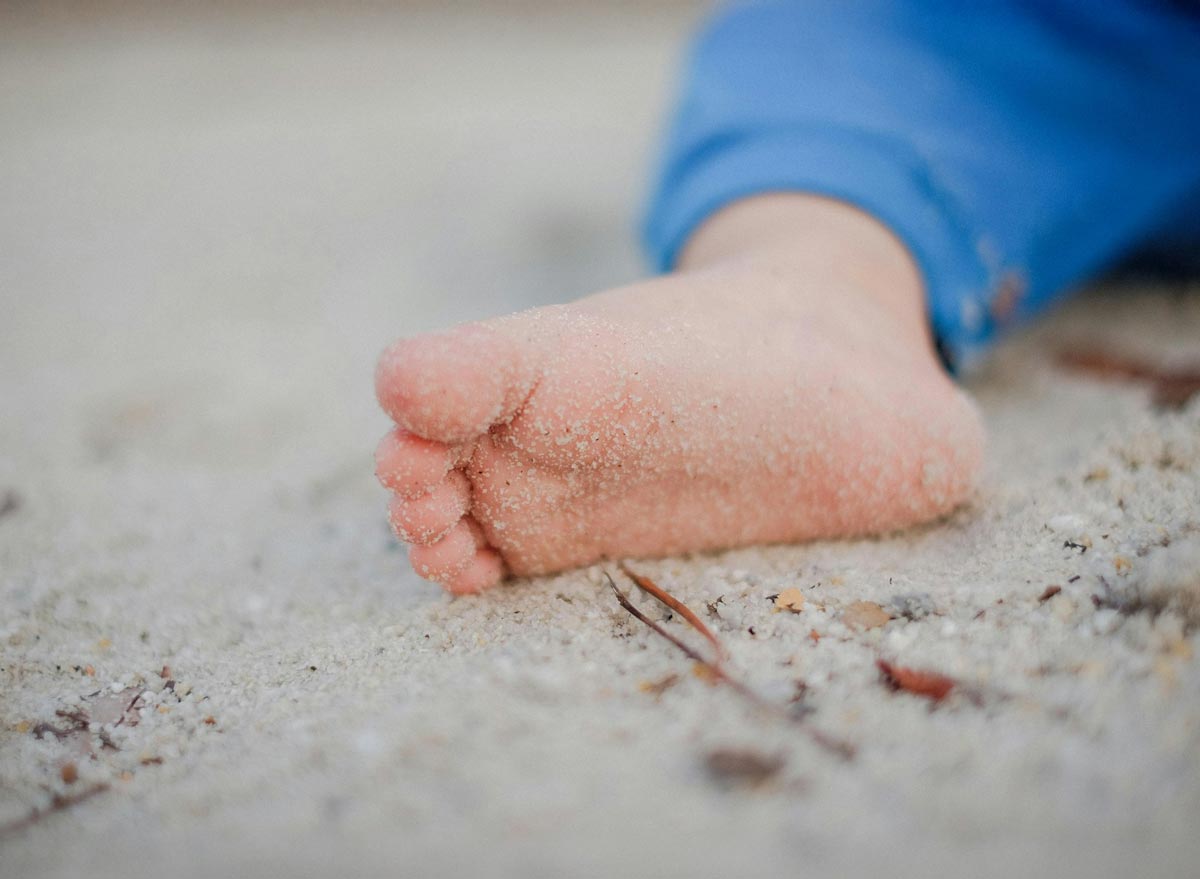 Frühe Unterstützung für Säuglinge und ihre Familien Kleiner Kinderfuß im Sand – Sinnbild für erste Schritte, Bindung und sanften Neubeginn